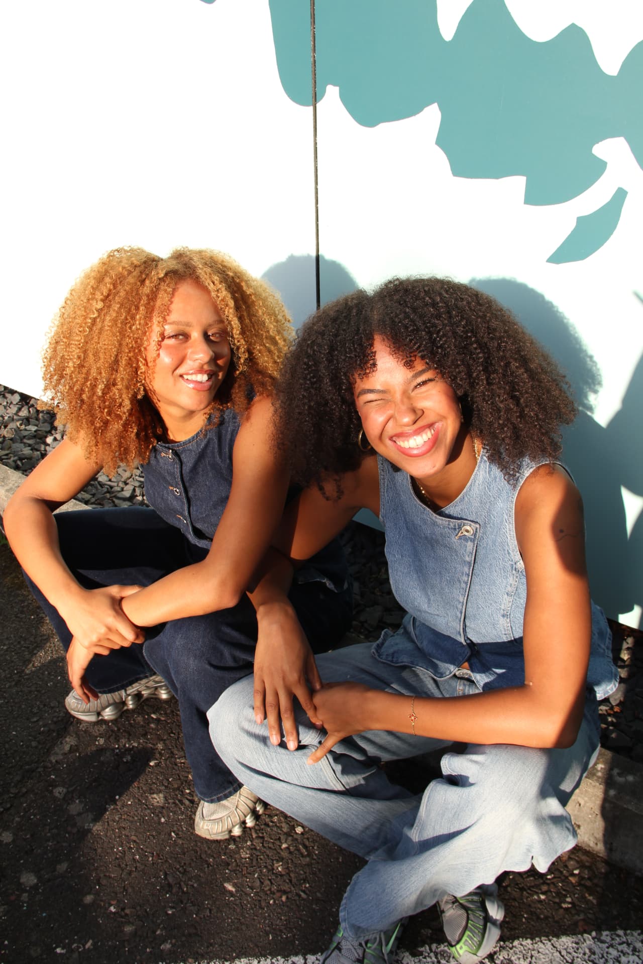 Malaika und Maria sitzen gemeinsam an einer Wand